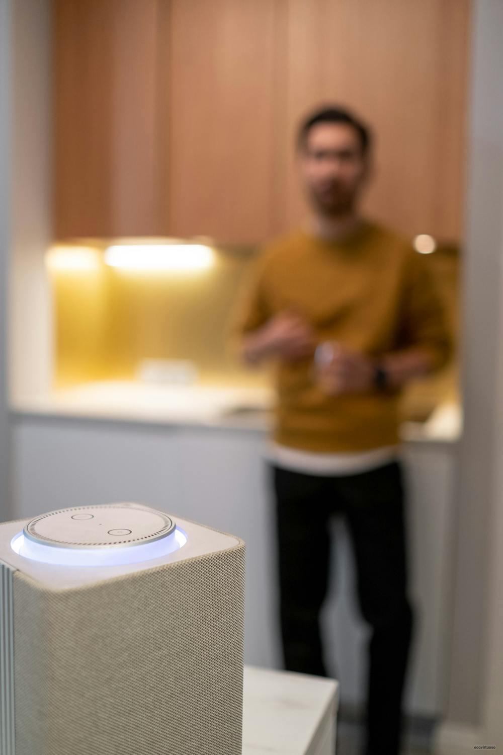 Man Standing in a Kitchen with a White Smart Speaker