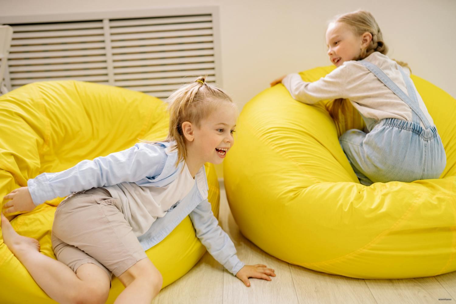 Two Pretty Blonde Girls Playing On Yellow Bean Bags